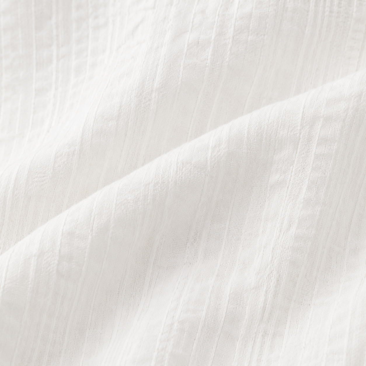 Close-up of the subtle textured white cotton fabric on the girls long sleeve blouse.