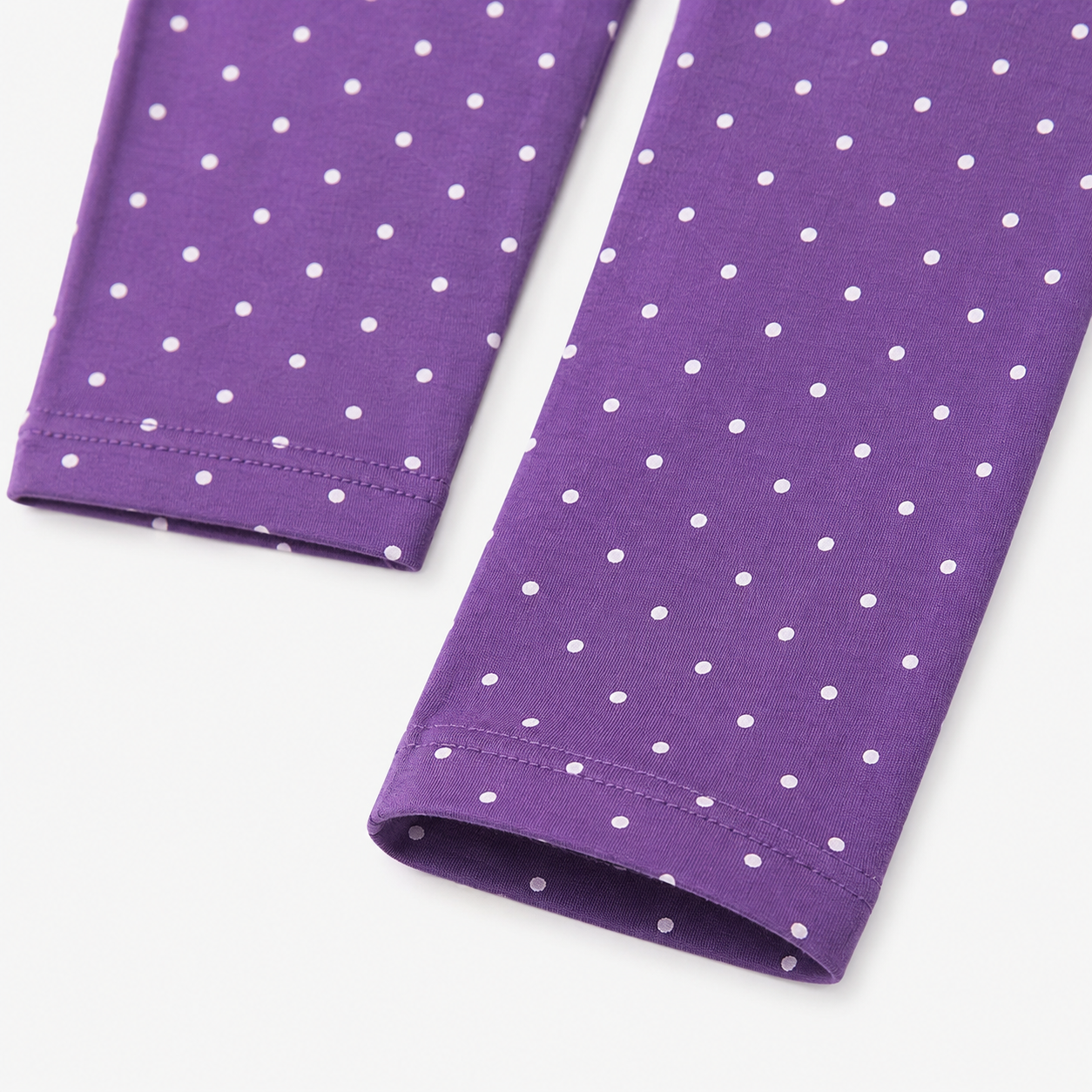 Close-up of the purple pants with small white polka dots and finished hems.
