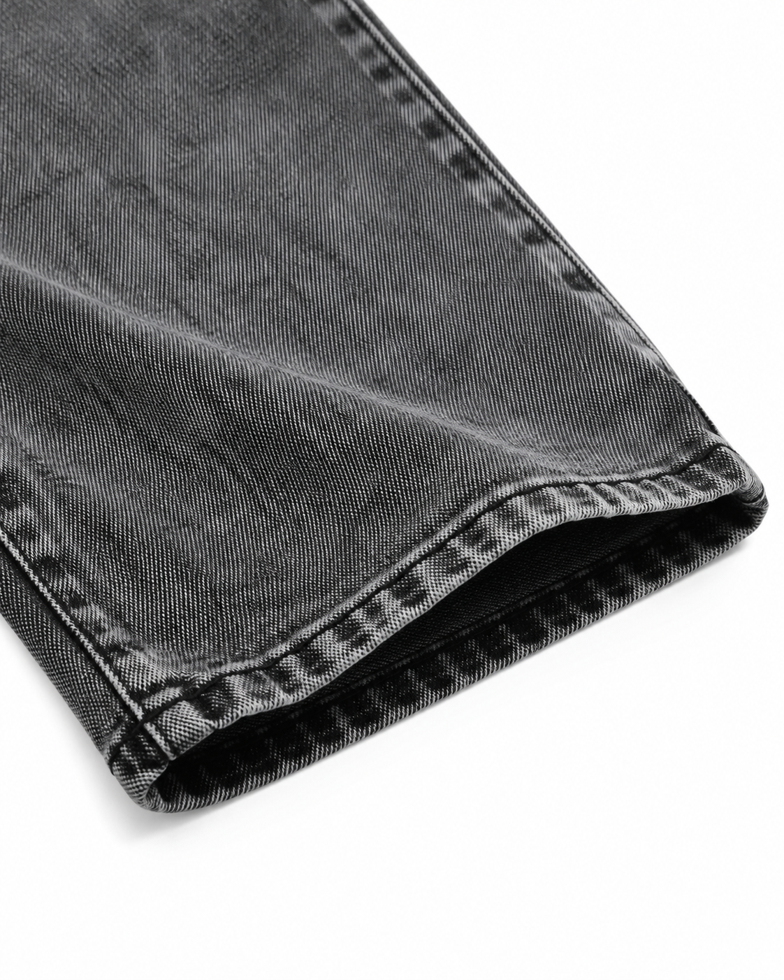 Close-up of the denim fabric, seam, and pant leg hem on the washed black jeans.