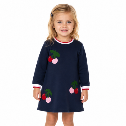 Girl wearing a navy long sleeve cherry dress on a white studio background.