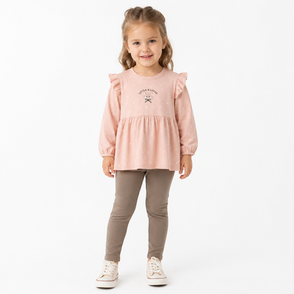 Girl model wearing a blush pink and taupe cotton set with a ruffle polka dot top and slim pants.