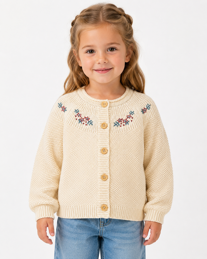 Toddler girl model wearing a cream embroidered cotton cardigan on a white studio background.