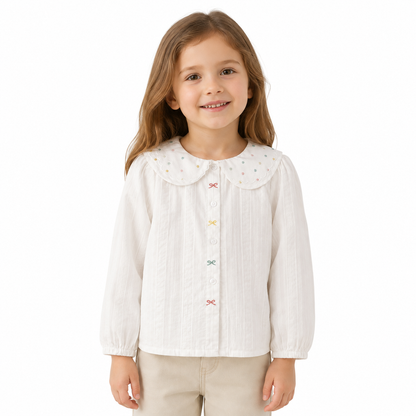 Girl model wearing a white long sleeve cotton blouse with a scalloped dotted collar on a white studio background.