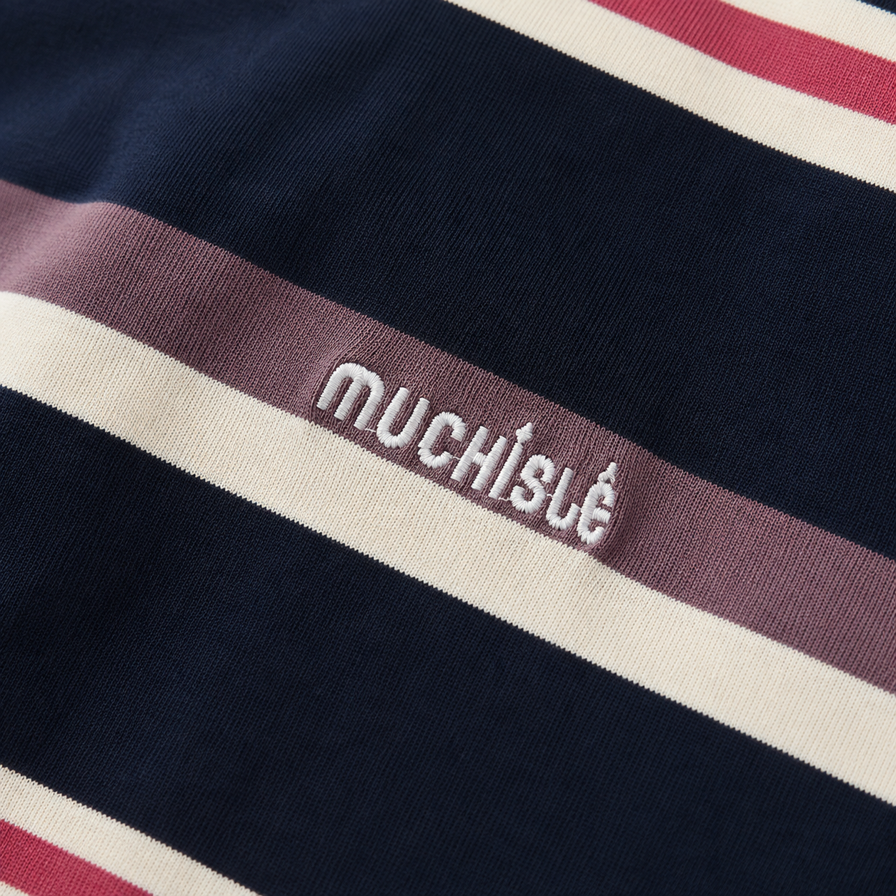 Close-up of the white embroidered chest detail on the navy, cream and mauve striped T-shirt.