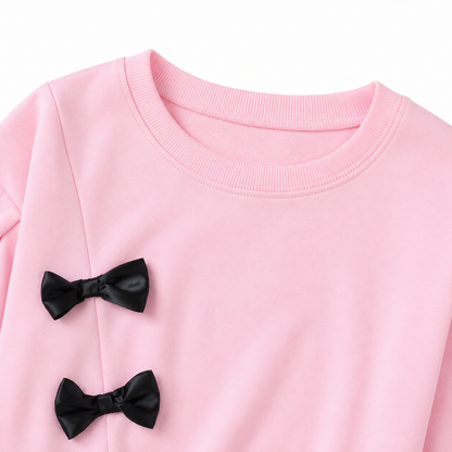 Close-up of the neckline and bow detail on the pink girls top.