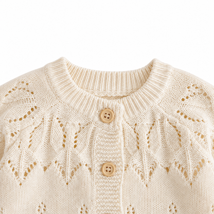 Close-up of the round ribbed neckline, cream button placket and openwork knit yoke on the girls cardigan.