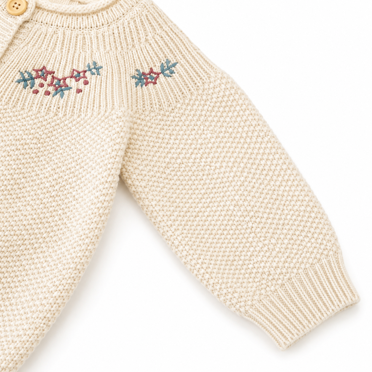 Close-up of the sleeve and cuff detail on a cream girls knit cardigan.