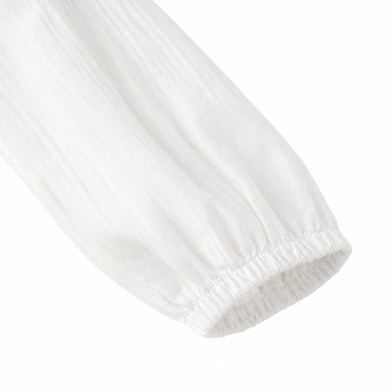 Close-up of the softly gathered long sleeve cuff on the white girls cotton blouse.