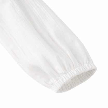 Close-up of the softly gathered long sleeve cuff on the white girls cotton blouse.