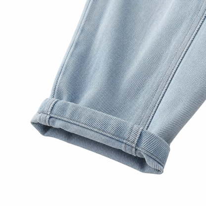 Close-up of rolled cuff detail on boys light blue denim joggers.