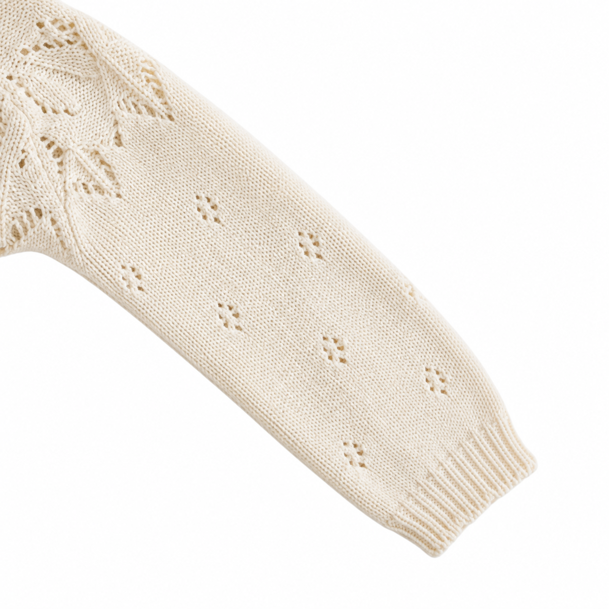 Close-up of the long sleeve, small eyelet knit details and ribbed cuff on the cream cotton cardigan.