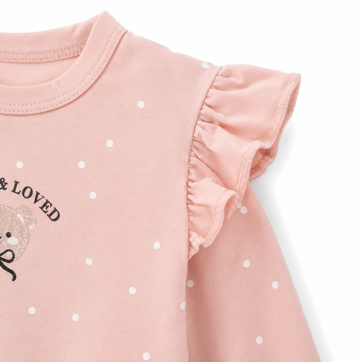 Close-up of the ruffle shoulder and sleeve detail on the blush pink polka dot girls top.