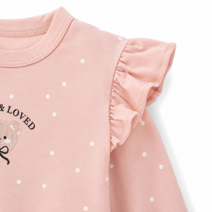 Close-up of the ruffle shoulder and sleeve detail on the blush pink polka dot girls top.