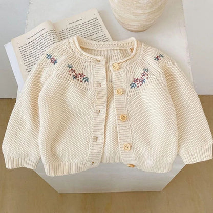 Close-up of the floral embroidery detail on a cream girls cardigan.