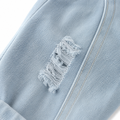 Close-up of distressed denim detail on boys light wash jeans.