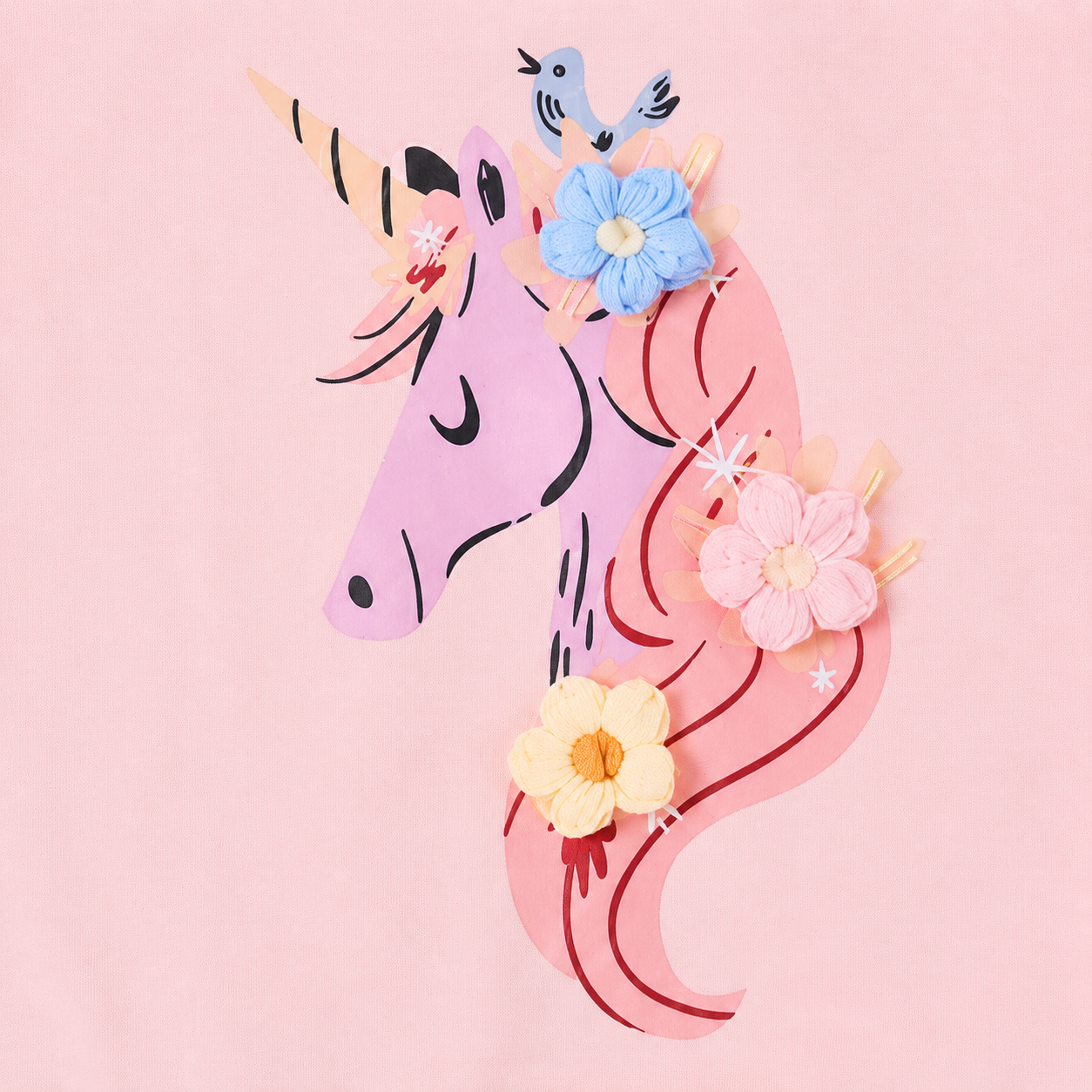 Close-up of the unicorn applique and floral accent detail on the front of a pink girls dress.
