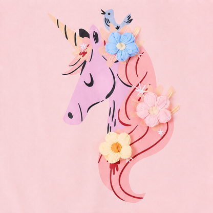 Close-up of the unicorn applique and floral accent detail on the front of a pink girls dress.