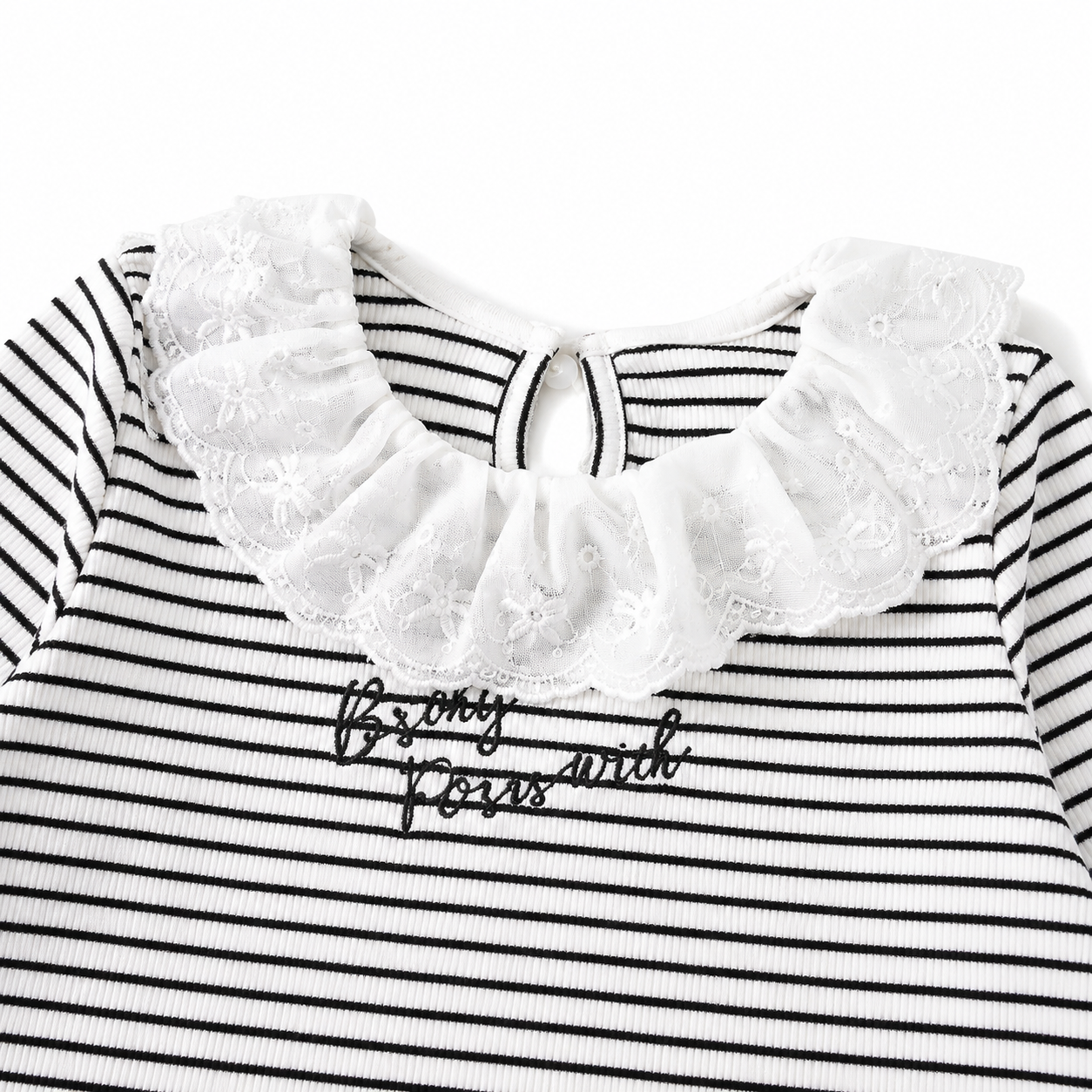 Close-up of the ruffle neckline and small decorative chest detail on a striped girls top.
