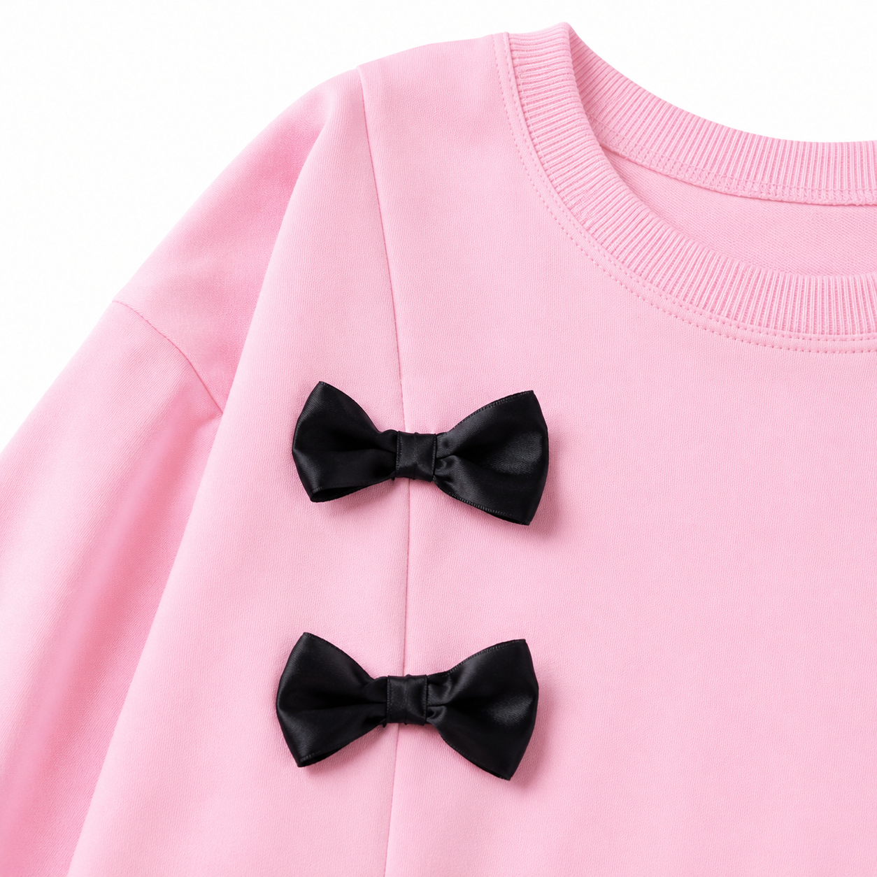Close-up of the double black bow detail on the front of the pink girls top.