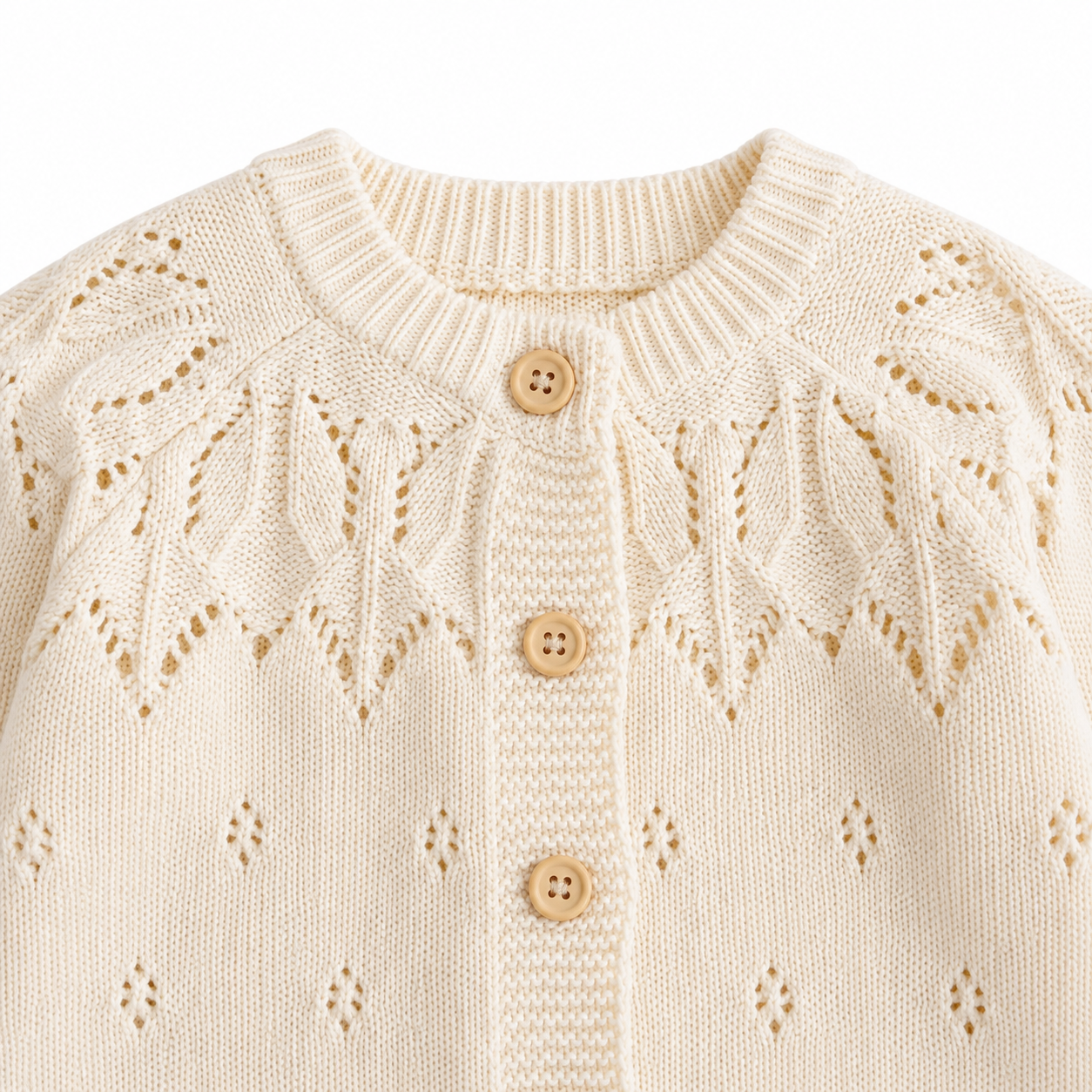 Detailed view of the leaf-pattern openwork yoke and button front on the cream girls knit cardigan.