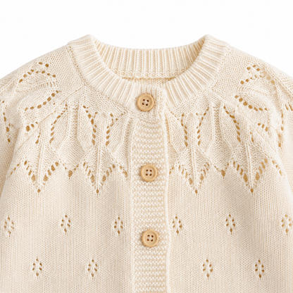 Detailed view of the leaf-pattern openwork yoke and button front on the cream girls knit cardigan.
