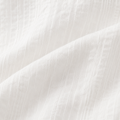 Close-up of the subtle textured white cotton fabric on the girls long sleeve blouse.