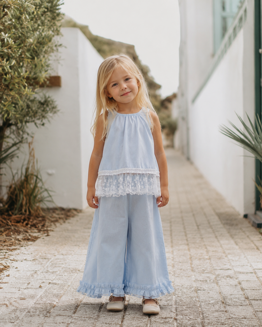 Young girl wearing the Bluebell Lace Set in light blue with a lace-trim top and wide-leg pants.