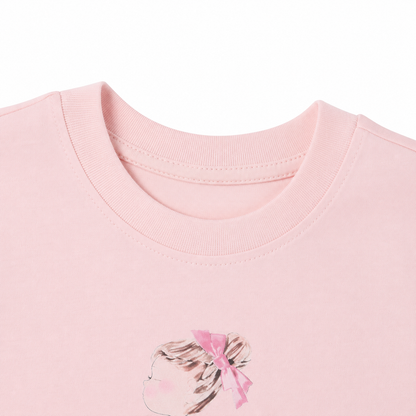 Close-up of the crew neckline and girl illustration on the blush pink T-shirt.