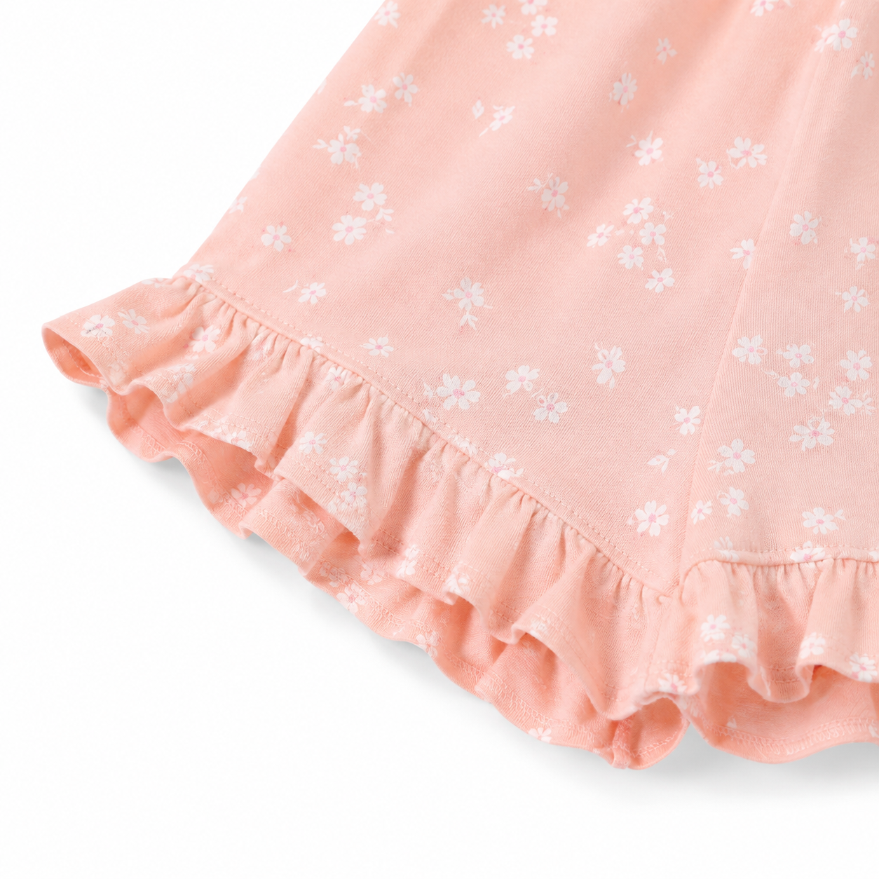 Close-up of the floral print and ruffle hem detail on the blush pink shorts.