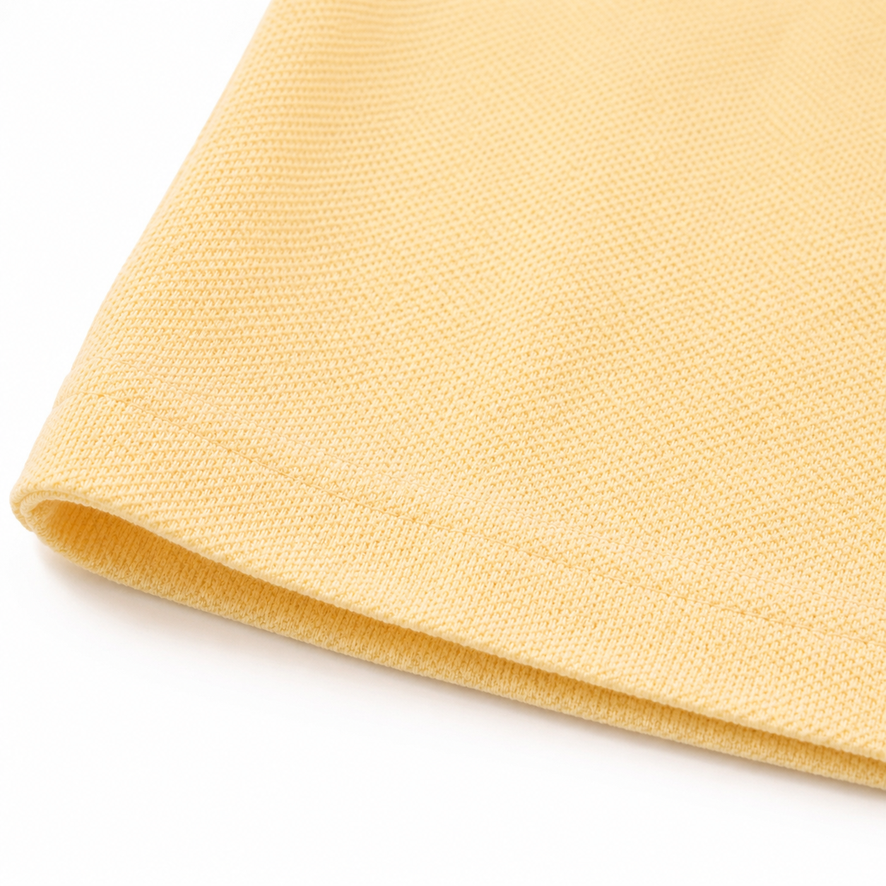 Close-up of the hem and fabric texture on the butter yellow kids polo shirt.