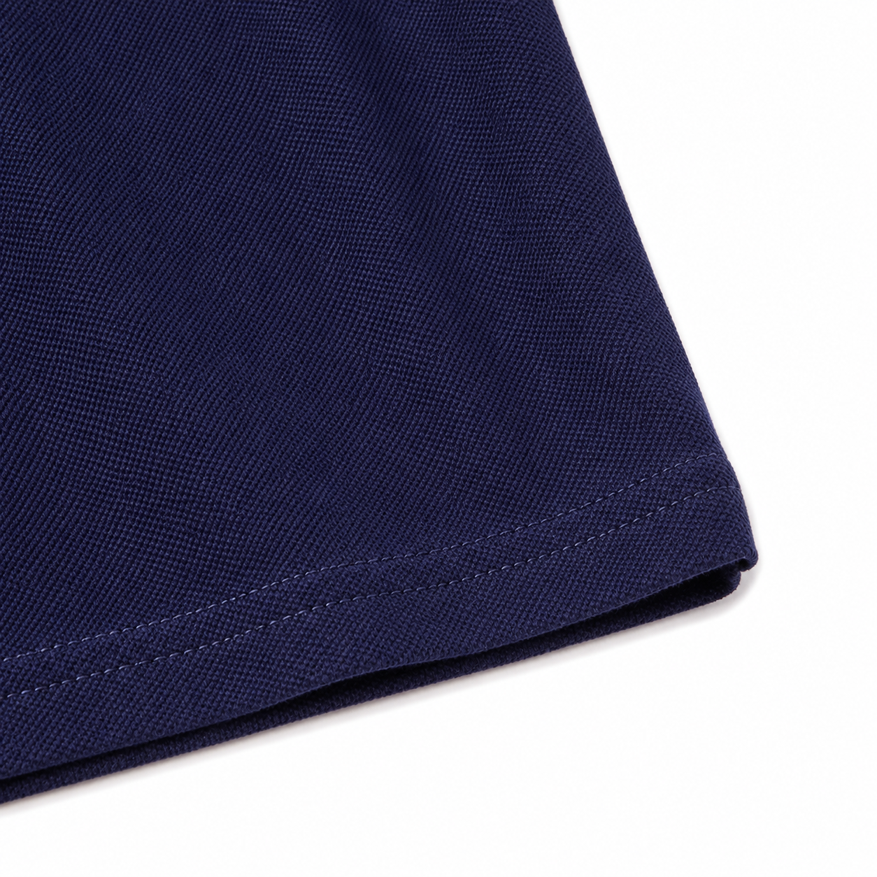 Close-up of the hem and fabric texture on the navy kids polo shirt.