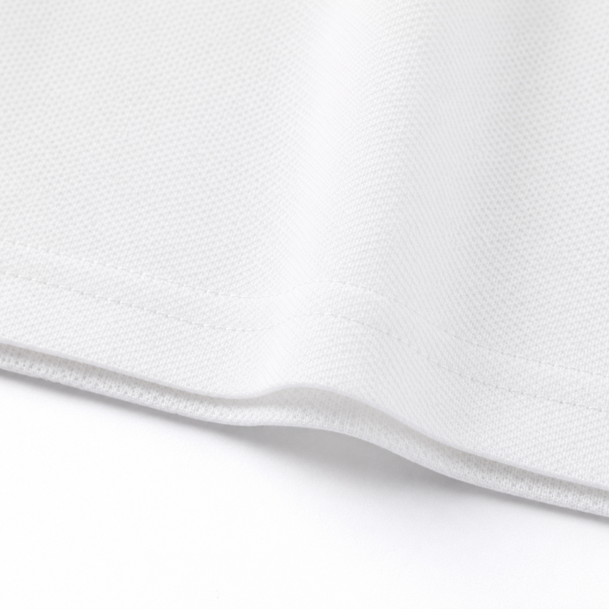 Close-up of the hem and fabric texture on the white kids polo shirt.