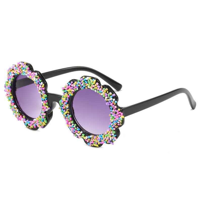 Black flower kids sunglasses with rainbow sprinkle details and UV400 purple tinted lenses.