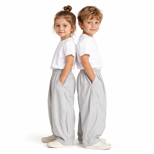 Girl and boy models wearing the light gray kids balloon pants with simple white tops.