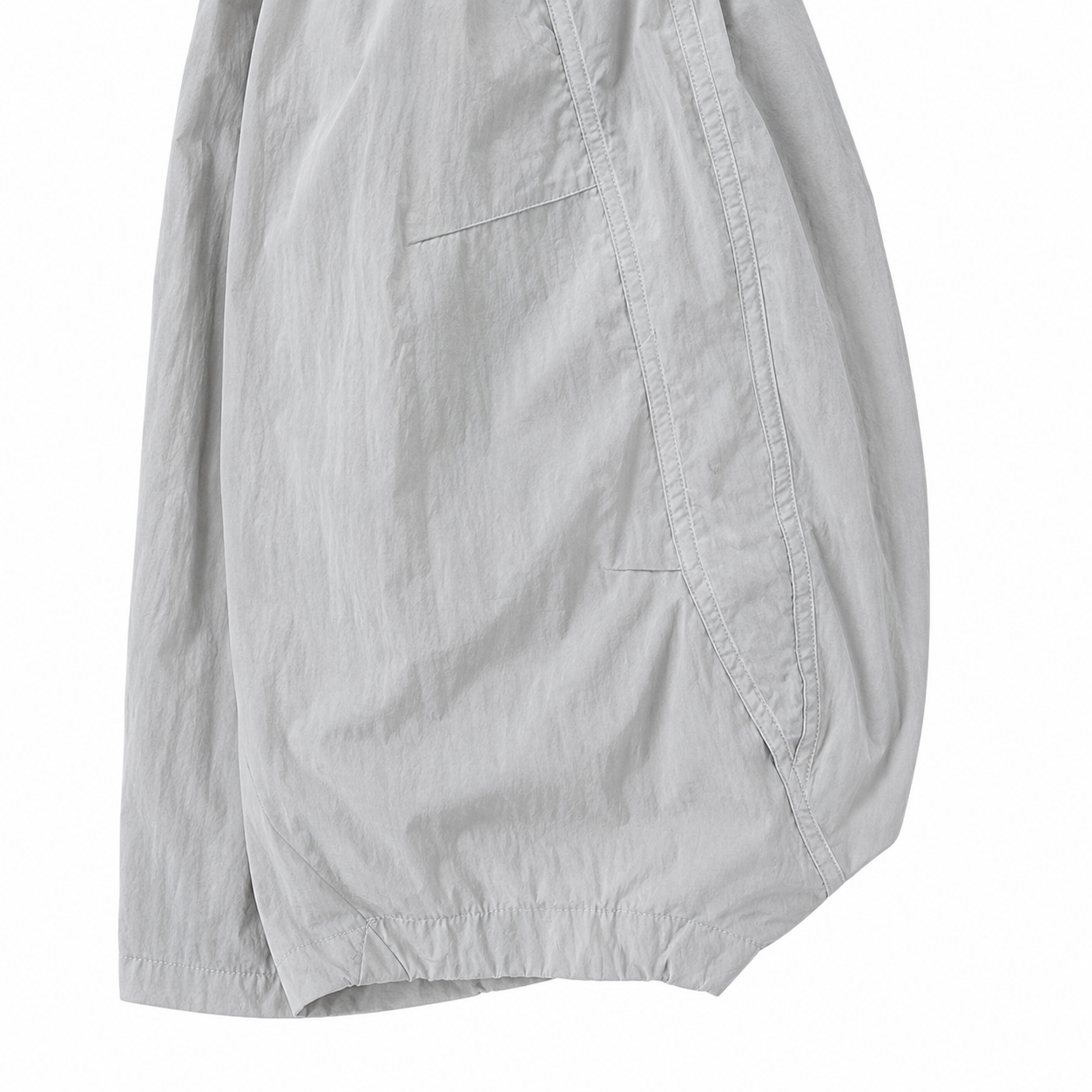 Close-up of the curved side seam and relaxed balloon-leg shape of the light gray kids pants.