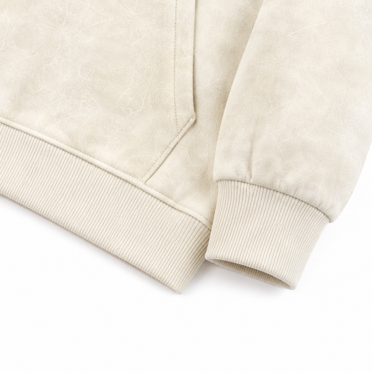 Close-up of the ribbed cuff and hem detail on the cream cotton hoodie.