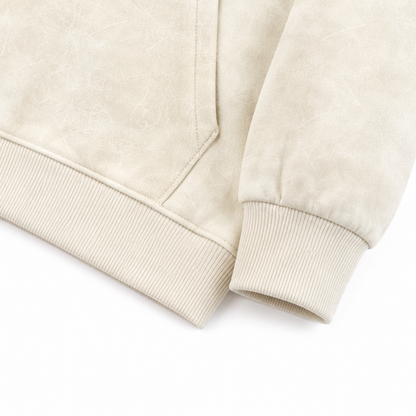 Close-up of the ribbed cuff and hem detail on the cream cotton hoodie.