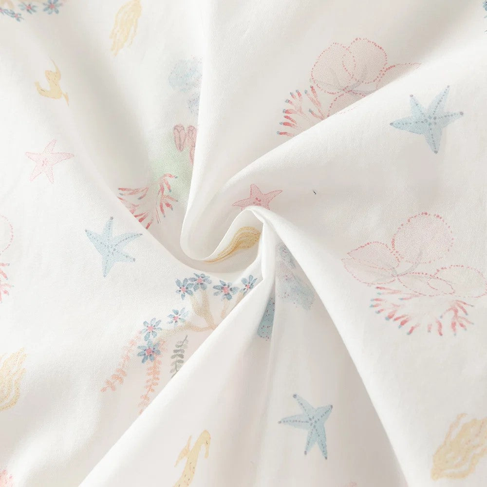 Close-up of the 100% cotton fabric with pastel starfish, shells, coral, seahorses and floral motifs.