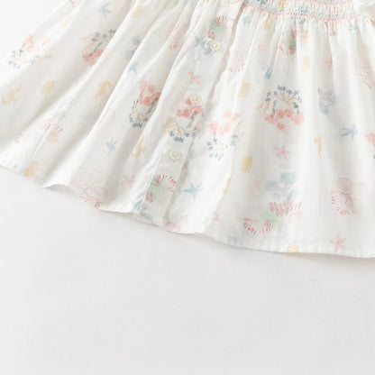 Close-up of the gathered hem, front buttons and pastel ocean print on the smocked girls blouse.