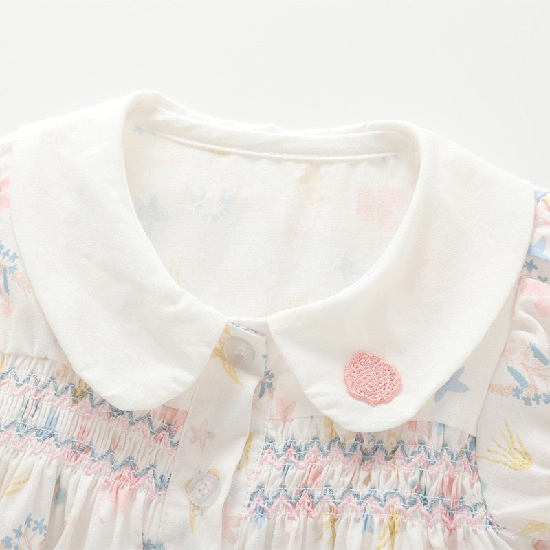 Close-up of the white Peter Pan collar and multicolor chest smocking on the girls cotton blouse.