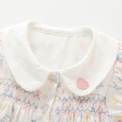Close-up of the white Peter Pan collar and multicolor chest smocking on the girls cotton blouse.