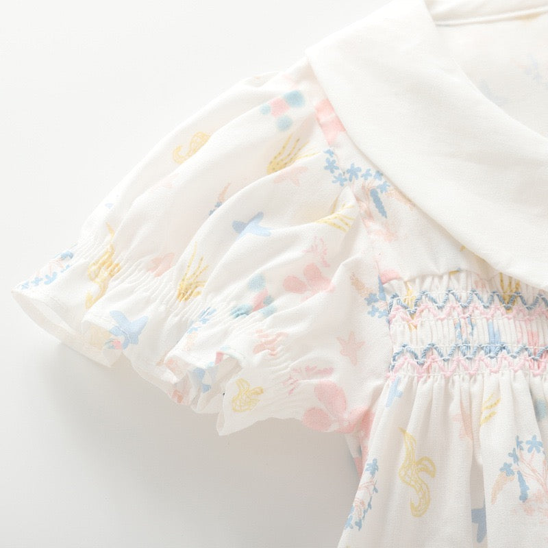 Close-up of the short puff sleeve and smocked chest detail on the white cotton girls blouse.