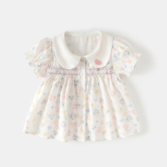 Front view of a white smocked girls cotton blouse with pastel sea life print, Peter Pan collar and puff sleeves.