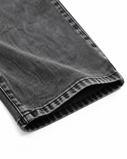 Close-up of the denim fabric, seam, and pant leg hem on the washed black jeans.