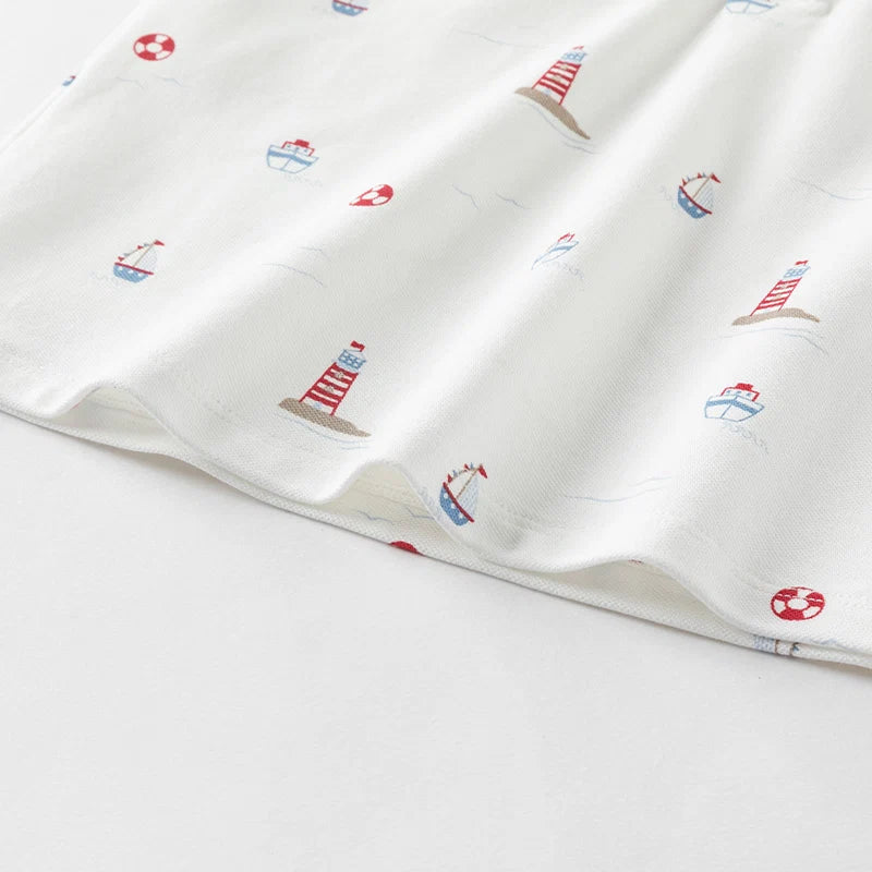 Close-up of the hem with lighthouse, sailboat and life ring prints on the boys polo shirt.