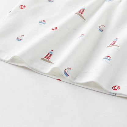 Close-up of the hem with lighthouse, sailboat and life ring prints on the boys polo shirt.