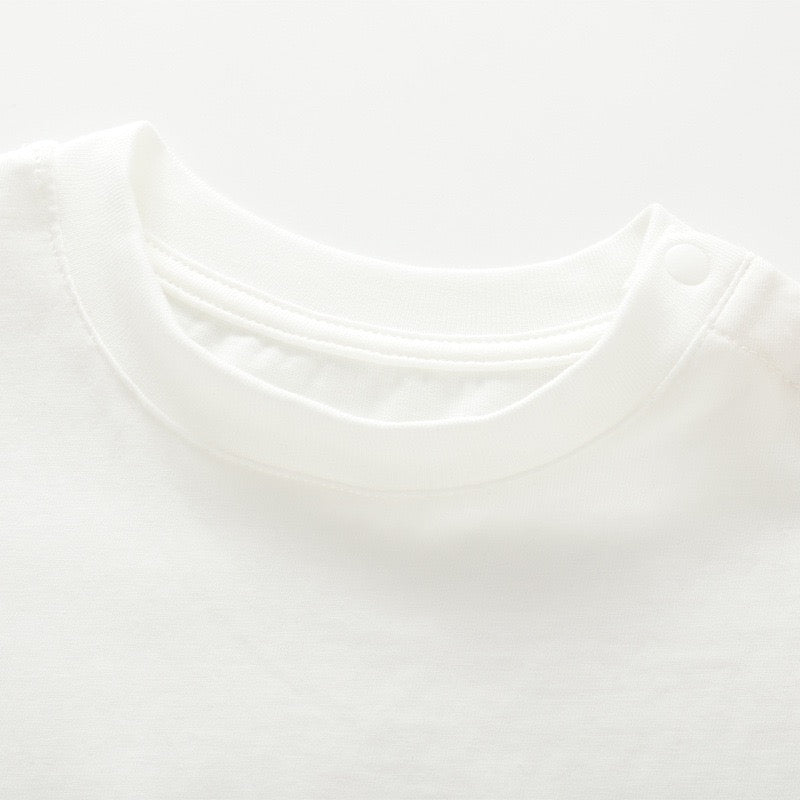 Close-up of the crew neckline and closed shoulder snaps on the white kids cotton T-shirt.