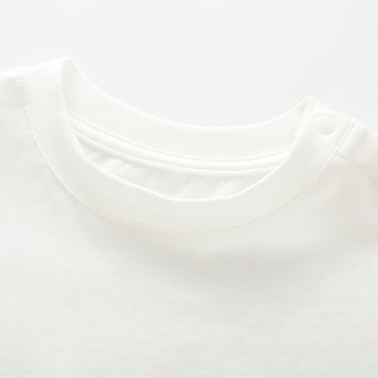 Close-up of the crew neckline and closed shoulder snaps on the white kids cotton T-shirt.