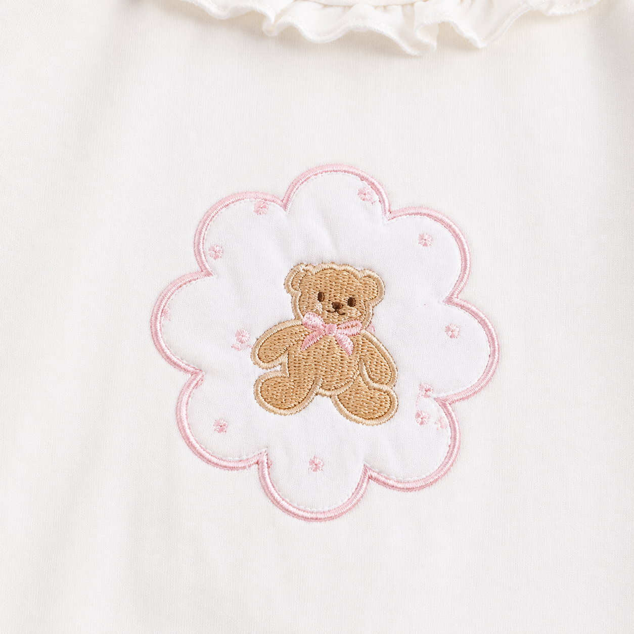 Close-up of the teddy bear framed by a flower outline on the Ivory girls cotton long sleeve top.