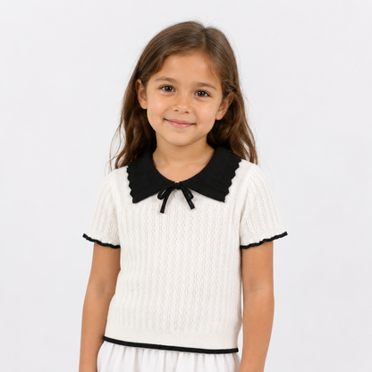 Girl model wearing an ivory bow collar knit top with black contrast trim on a white background.